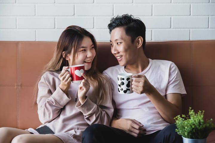 romantic couple drinking coffee on couch