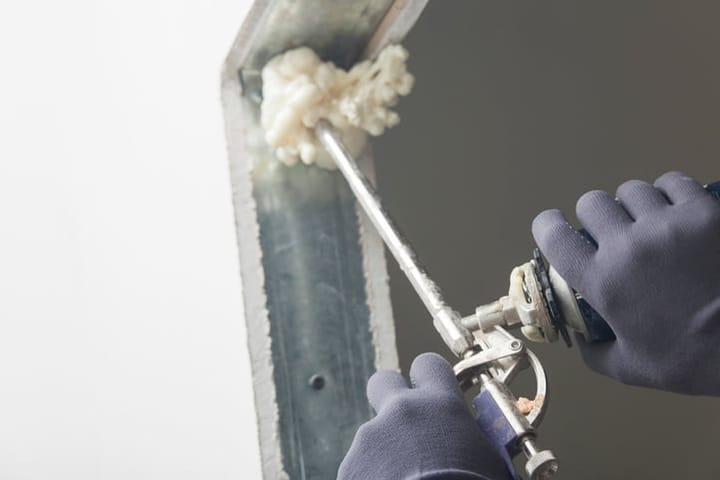 Construction site worker using a can of expanding foam