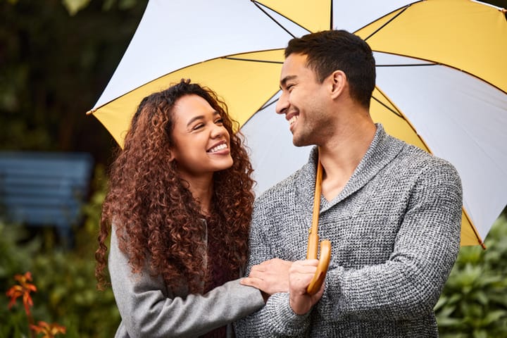 smiling black couple under umbrella
