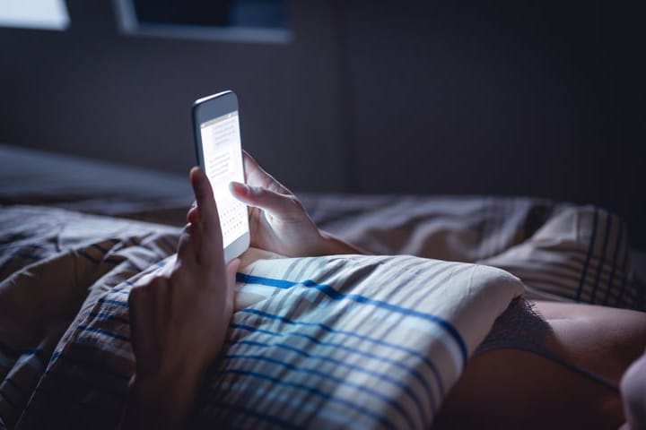 woman's hands texting in dark room