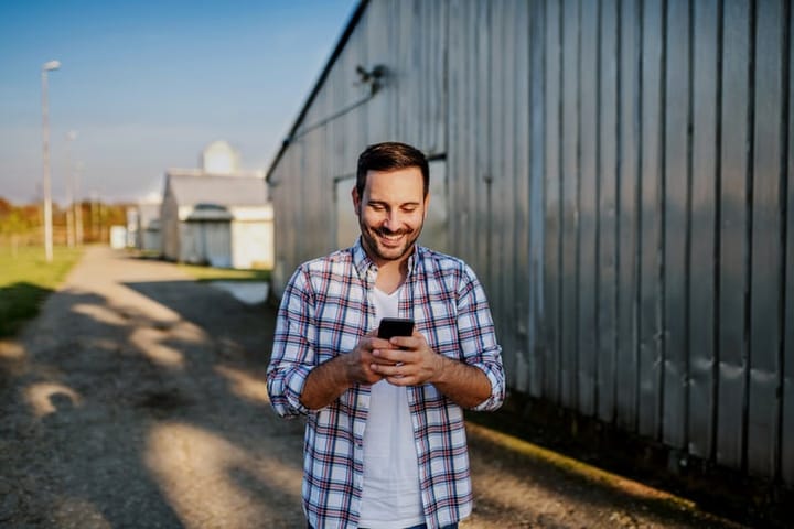 man smiling texting plaid shirt