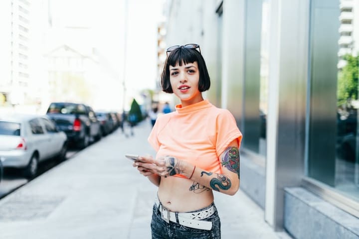 hipster woman with tattoos holding mobile