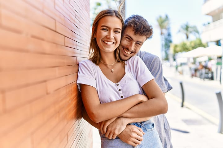 couple hugging beside wall
