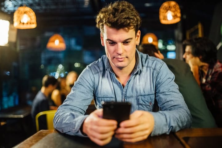 young man in denim holding mobile