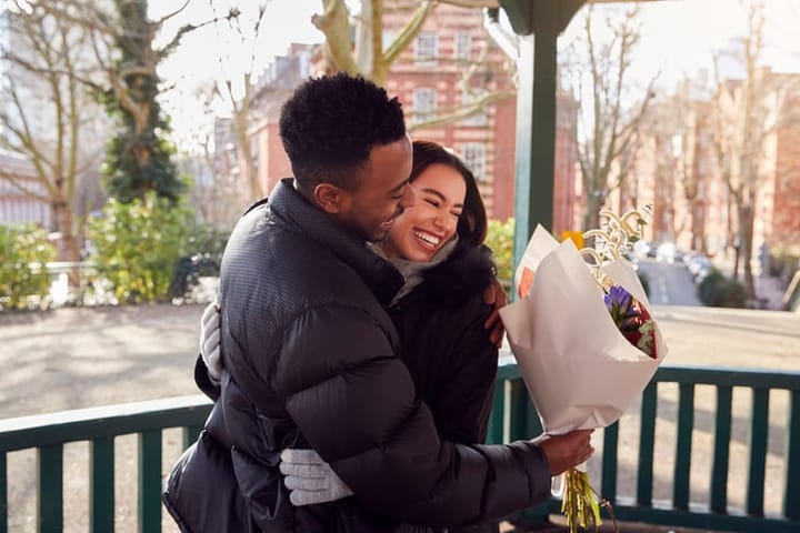 man bringing smiling woman flowers