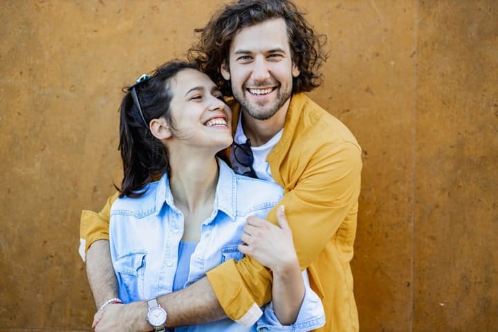 Portrait of cute couple laughing yellow background