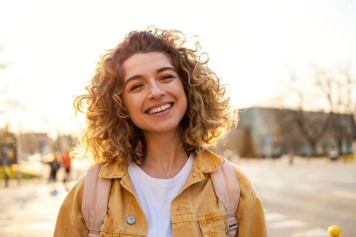 curly haired woman smiling in the sunset