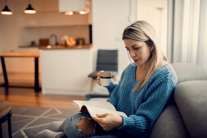 woman reading book on couch