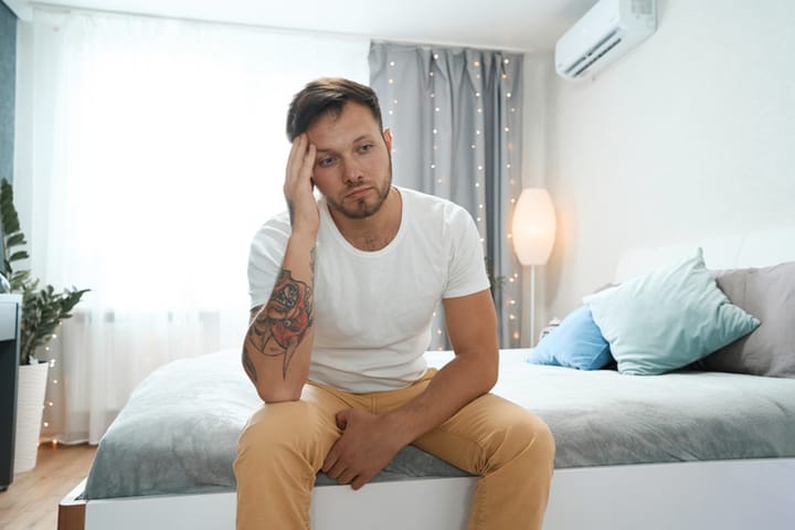 man on bed looking sad