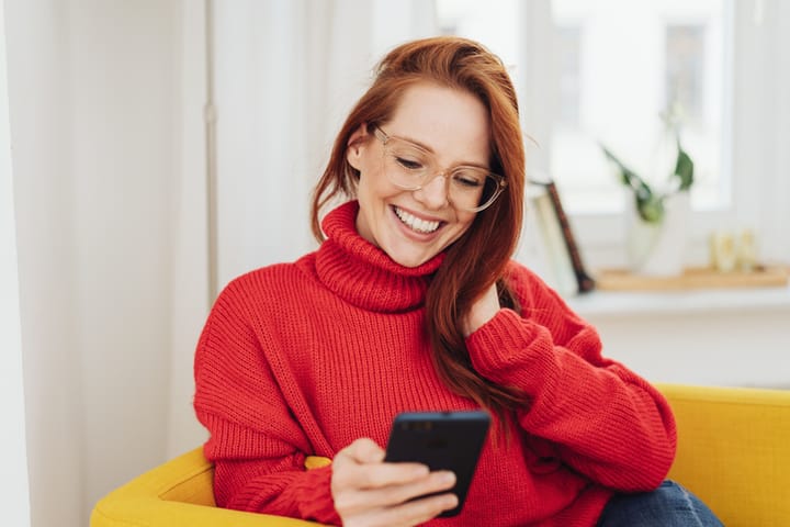 smiling woman texting on couch