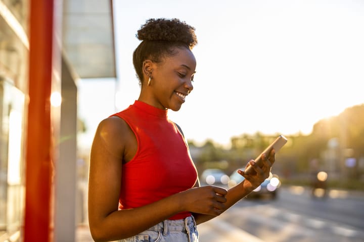 smiling black woman texting outdoors