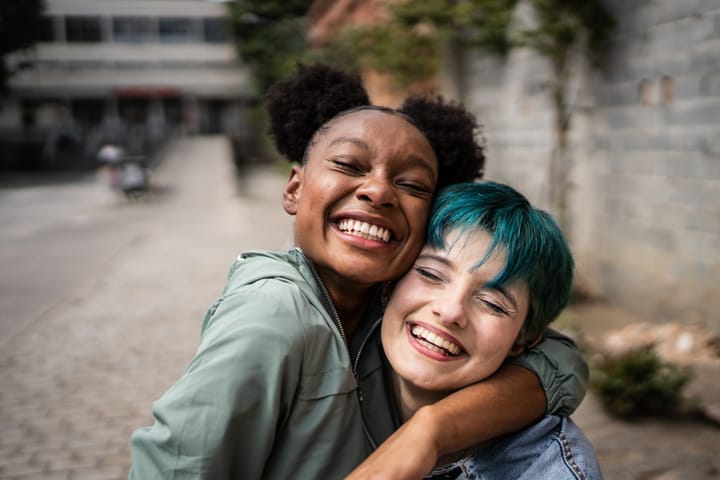 happy friends embracing in street