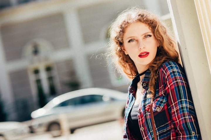 Beautiful woman with long blond curly hair in urban background.