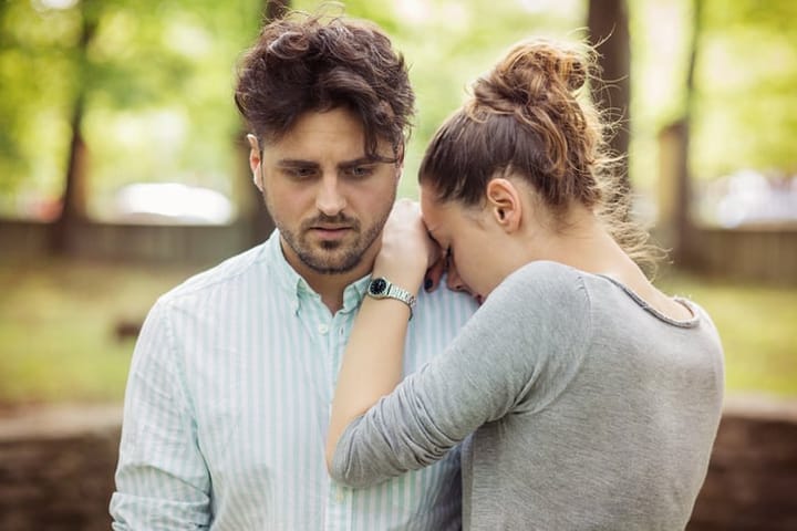 girl crying on man's shoulder