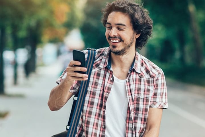 curly haired man texting