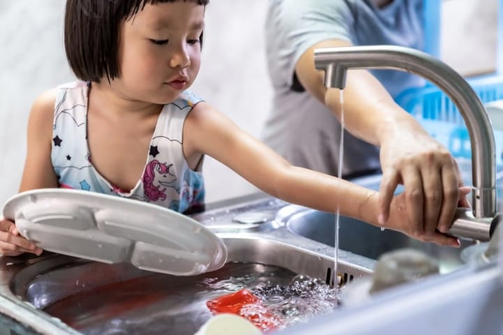 Girl and mom washing dishes.