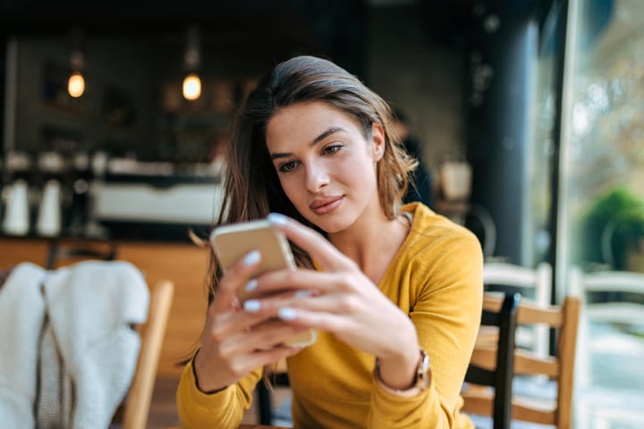 smiling woman texting at cafe