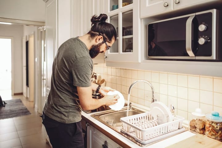 Young man washing dishes at home.