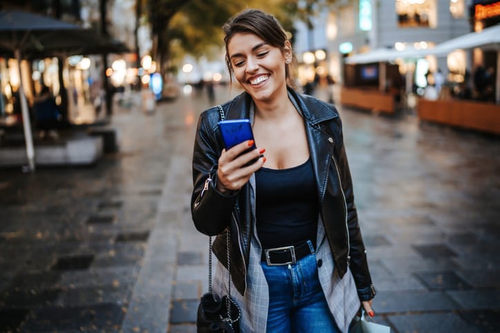smiling woman holding mobile in the city