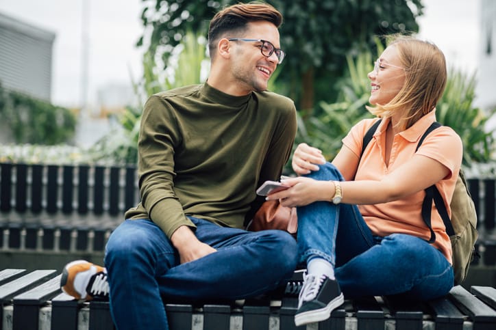 young couple sitting on park bench