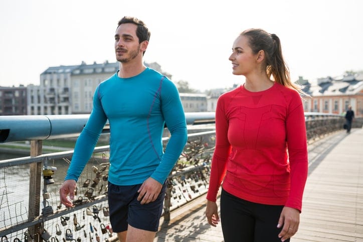 Fitness young man and woman walking together over a walkway bridge in city in morning