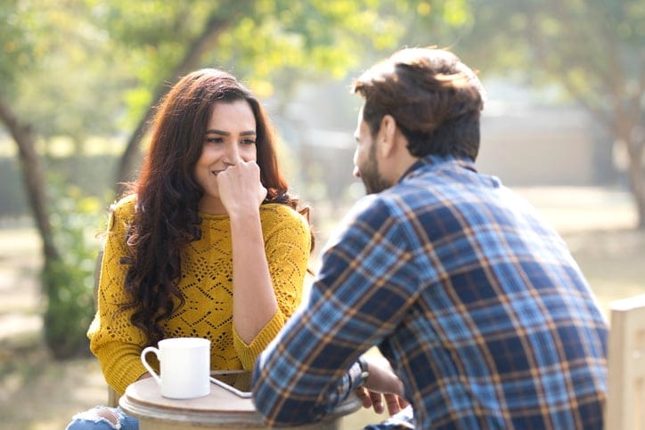 Happy young couple with digital tablet and coffee cup at park