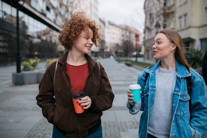 two female friends walking with coffee