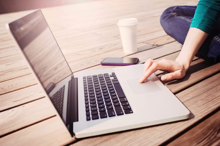 Laptop on table with user and mobile