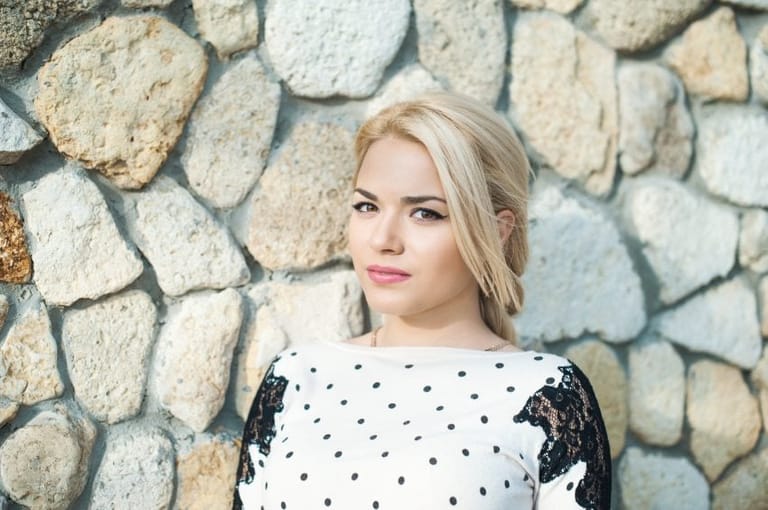 Portrait of a pretty young girl at a stone wall