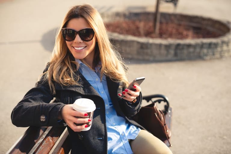 brunette woman texting on park bench