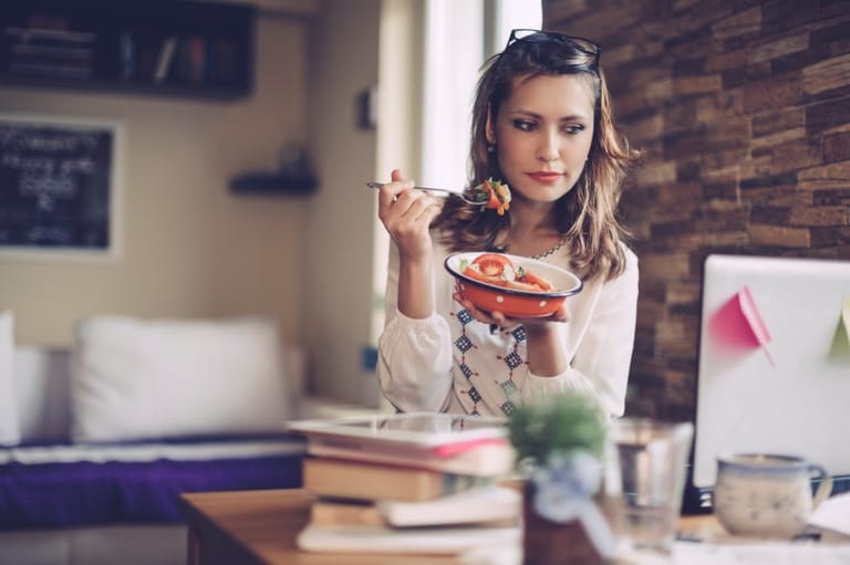 woman eating salad at computer