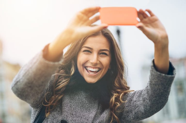smiling woman taking selfie outdoors