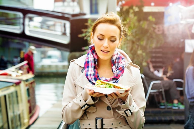 Young woman with salad walking outdoors.