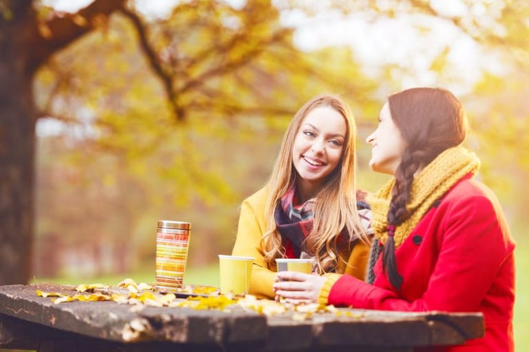 Two friends chatting outdoors autumn