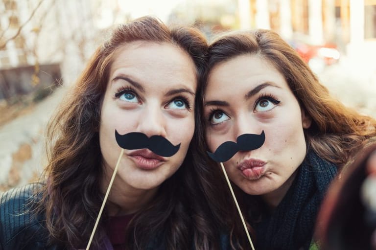 Best friends posing with fake mustaches.