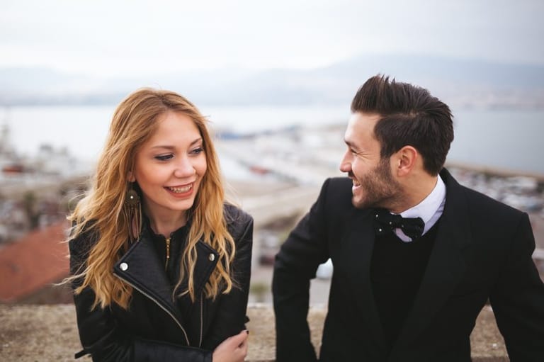 Couple sat on wall laughing