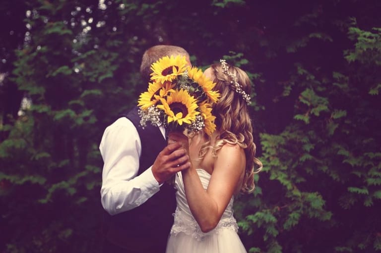 Bride and groom behind flower