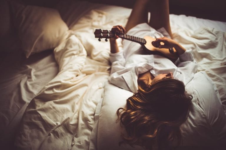 Girl laid in bed with guitar