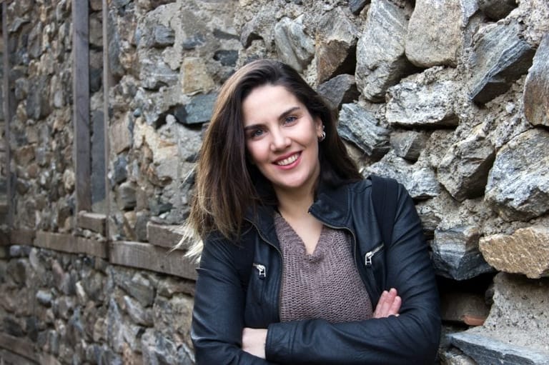 Brunette standing by wall smiling