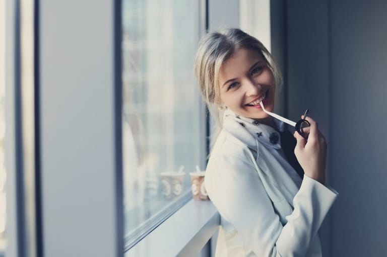 Young blonde smiling holding glasses