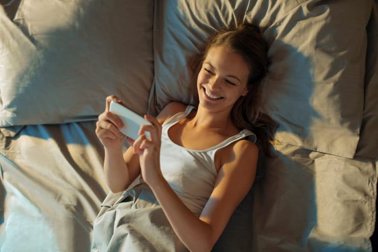 Girl laid in bed with smartphone