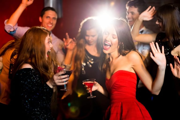 Female friends drinking and dancing at a party.