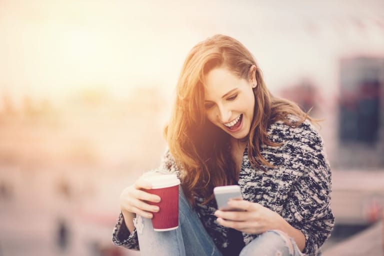 woman texting laughing sunset