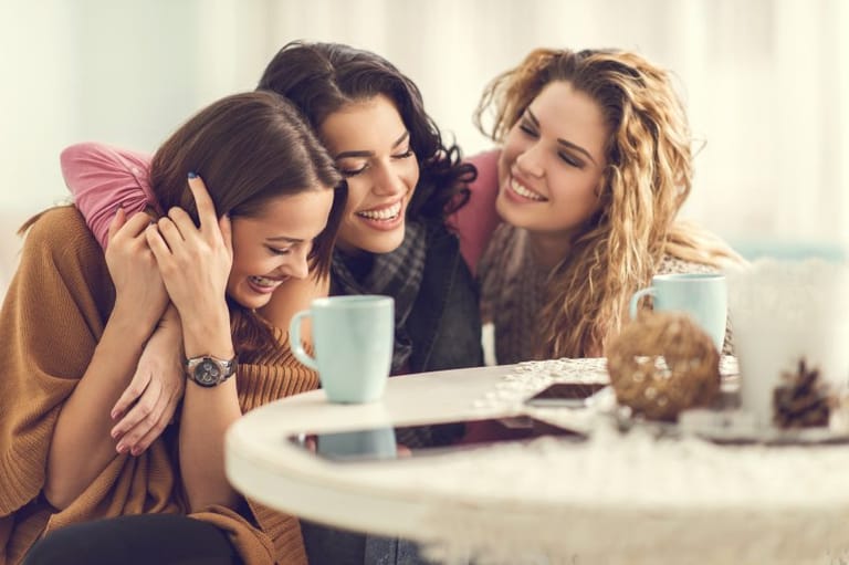 three happy women laughing coffee shop