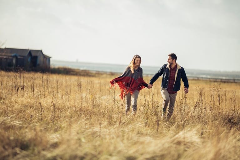 couple holding hands walking field