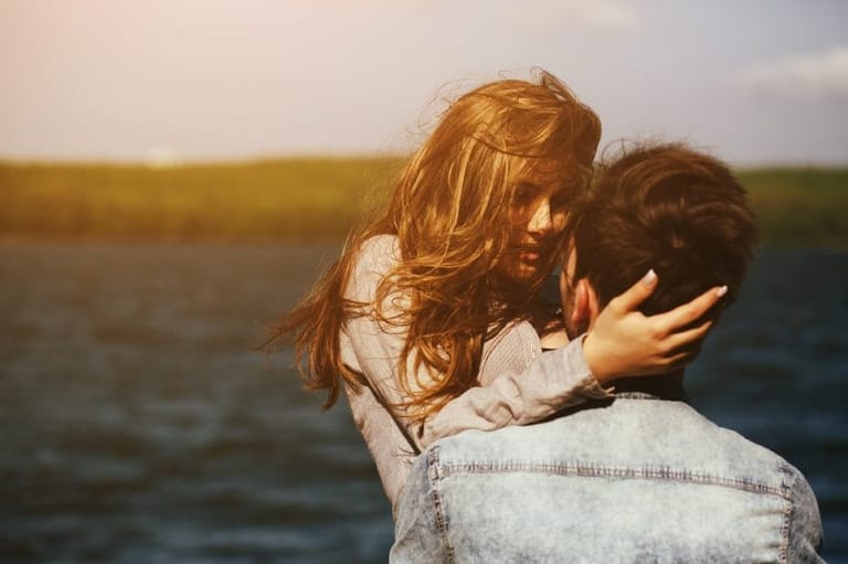 couple embracing at lake on windy day