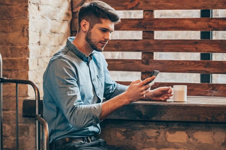 young man texting with coffee