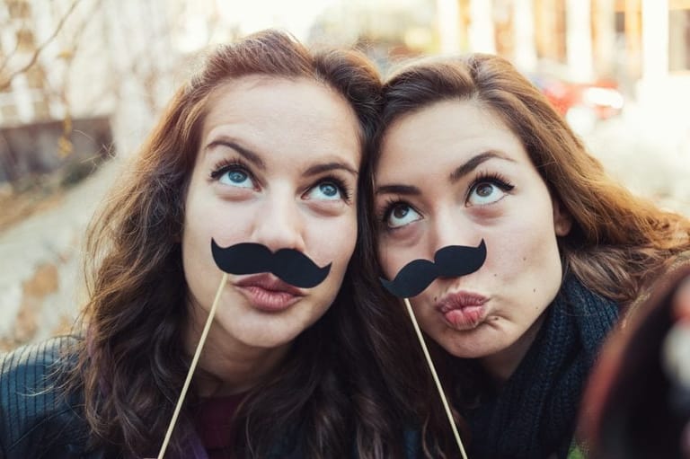 Best friends posing with fake mustaches.