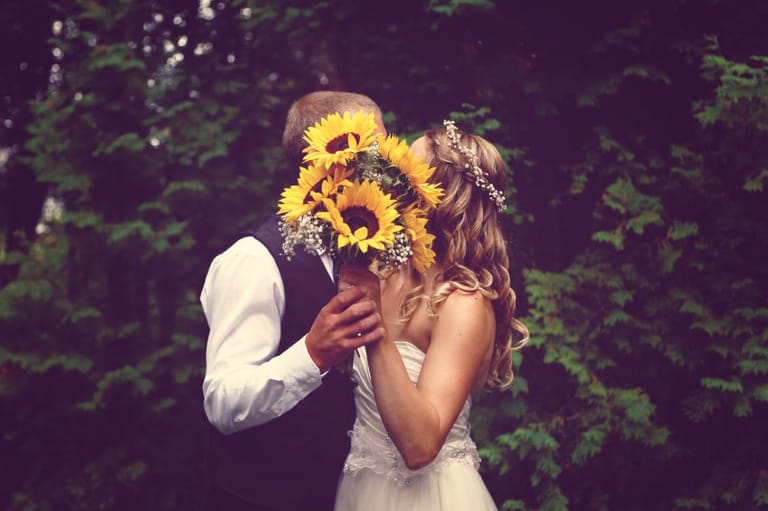 Bride and groom behind flower