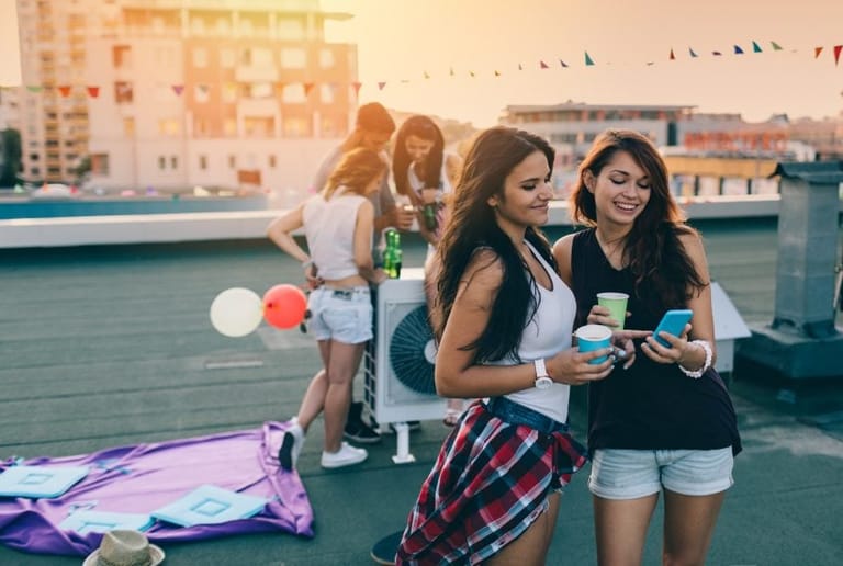 female friends reading texts at rooftop party